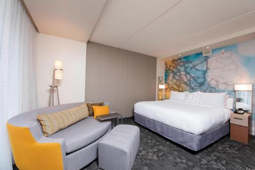 um quarto de hotel com uma cama e um sofá em Courtyard by Marriott Holland Downtown em Holland