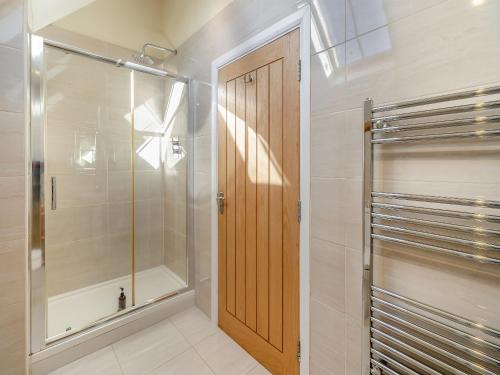 a bathroom with a shower and a wooden door at The Old Chapel in Spark Bridge