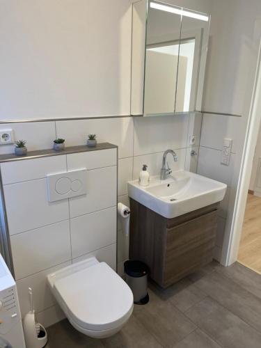 a white bathroom with a toilet and a sink at Schöne Ferienwohnung mit eigenem Stellplatz in Detmold