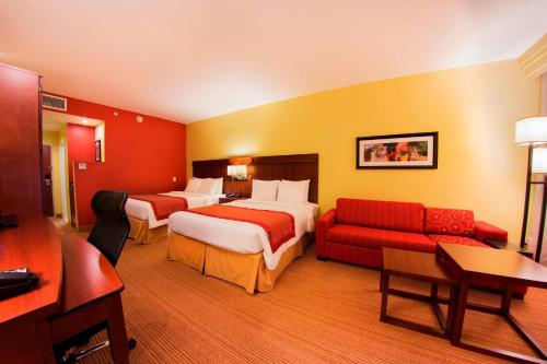 una camera d'albergo con due letti e un divano di Courtyard by Marriott Paramaribo a Paramaribo
