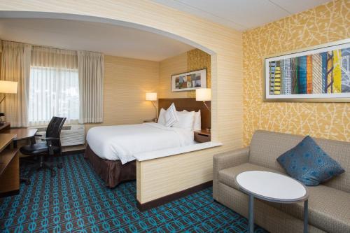 a hotel room with a bed and a desk and a couch at Fairfield Inn Manchester - Boston Regional Airport in Manchester