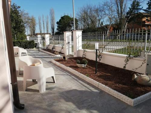 a patio with white chairs and a white fence at MAWA in Ferrara