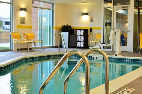 Fairfield Inn & Suites by Marriott Omaha Northwest في أوماها: مسبح وكراسي صفراء وطاولات في مبنى