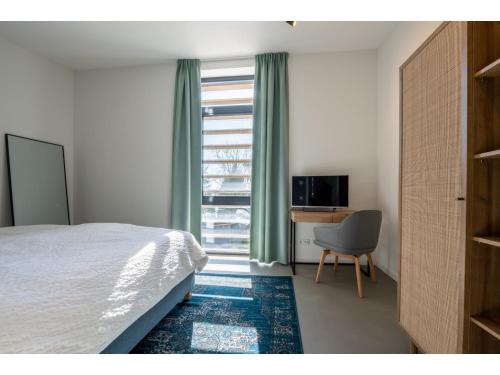 ein Schlafzimmer mit einem Bett, einem Stuhl und einem Fenster in der Unterkunft completely newly built modern holiday home in a quiet location in Kamperland