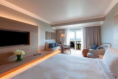 a hotel room with a large bed and a flat screen tv at Praia D'El Rey Marriott Golf & Beach Resort in Casal da Lagoa Seca