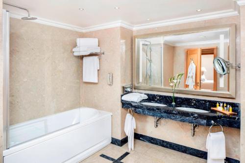 uma casa de banho com uma banheira, um lavatório e um espelho. em Praia D'El Rey Marriott Golf & Beach Resort em Praia del Rei