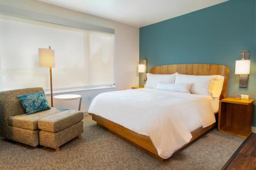 a bedroom with a large bed and a chair at Element Sacramento Airport in Sacramento