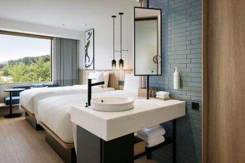 a bathroom with a sink and a bed with a mirror at Fairfield by Marriott Hyogo Kannabe Highland in Toyooka