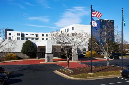 a building with an american flag in a parking lot at Sheraton Richmond Airport Hotel in Sandston