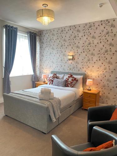 a bedroom with a large bed with floral wallpaper at Coastal Waters (Hotel Barton) in Torquay