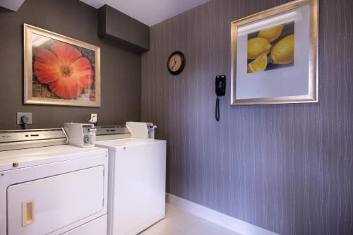 a laundry room with a washer and dryer and a clock at Courtyard by Marriott Oxnard/Ventura in Oxnard