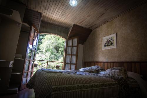 a bedroom with a bed and a large window at Hotel Vill' Agi in Campos do Jordão