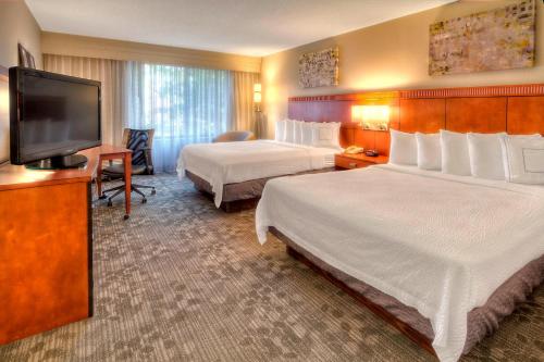 a hotel room with two beds and a flat screen tv at Courtyard Memphis Germantown in Memphis