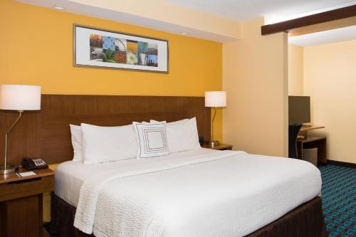 una habitación de hotel con una cama grande con sábanas blancas en Fairfield by Marriott Inn & Suites Raynham Middleborough/Plymouth en Middleboro