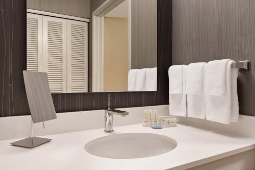 a bathroom with a sink and a mirror and towels at Courtyard by Marriott Topeka in Topeka