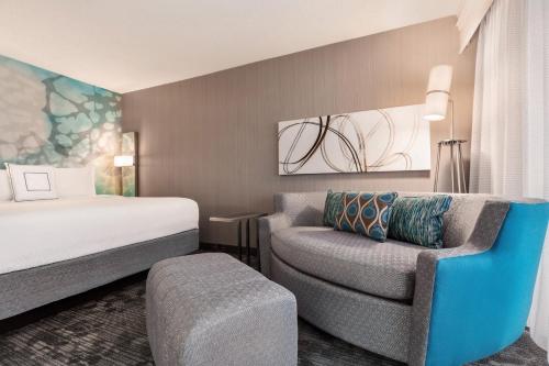 トピカにあるCourtyard by Marriott Topekaのベッドと椅子付きのホテルルーム
