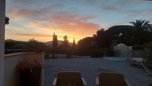 a sunset in a yard with chairs and trees at Podere Grandolfi B&B in Capoliveri