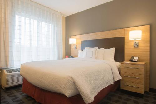 TownePlace Suites by Marriott Syracuse Clay في ليفربول: غرفة فندقية بسرير كبير ونافذة