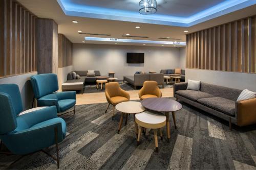 uma sala de espera com sofás, mesas e cadeiras em TownePlace Suites by Marriott New York Brooklyn em Brooklyn