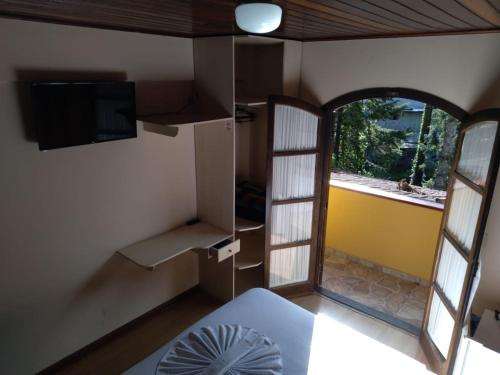 a room with a bed and a tv and a window at Hotel Vill' Agi in Campos do Jordão