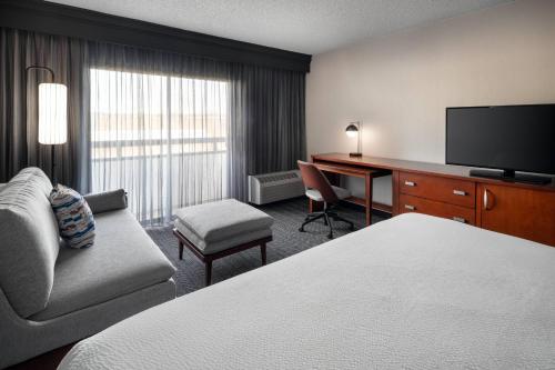 a hotel room with a bed and a desk and a television at Courtyard Seattle Southcenter in Tukwila