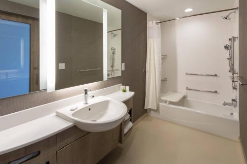 a bathroom with a sink and a tub and a mirror at SpringHill Suites Minneapolis Maple Grove/Arbor Lakes in Maple Grove