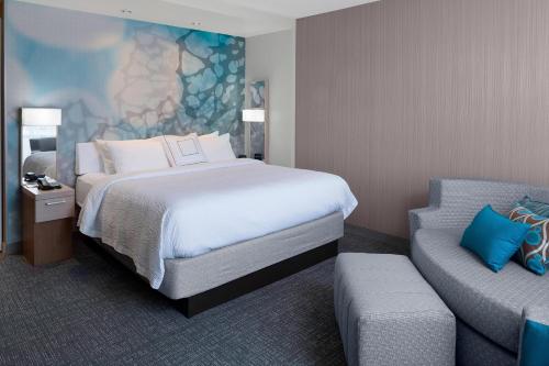 a hotel room with a bed and a couch at Courtyard by Marriott Dallas Flower Mound in Flower Mound