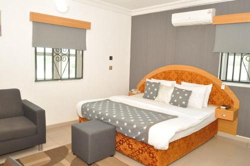 a bedroom with a large bed and a chair at Ne-yo hotel & rv lodges in Asaba