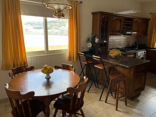 una cocina con mesa de madera con sillas y una isla de cocina en Groundfloor Apartment By The Sea, Fabulous Views en St Paul's Bay