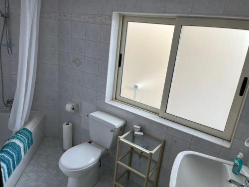 a bathroom with a toilet and a sink and a window at Groundfloor Apartment By The Sea, Fabulous Views in St Paul's Bay
