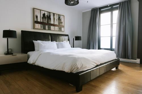 a bedroom with a large bed with white sheets at Lofts du Vieux-Port by Gray Collection in Montréal