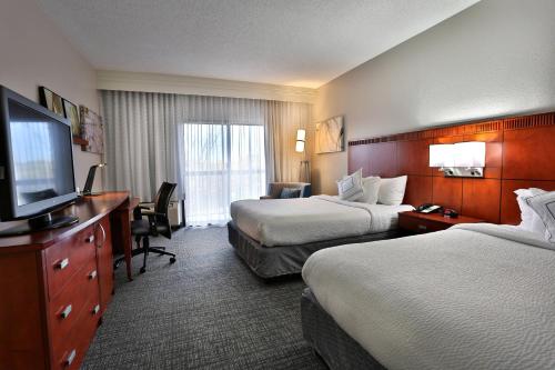 a hotel room with two beds and a flat screen tv at Courtyard Montgomery in Montgomery
