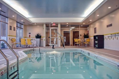 ein Pool in einem Hotel mit gelben Stühlen und Tischen in der Unterkunft Fairfield Inn & Suites by Marriott Reading Wyomissing in Wyomissing