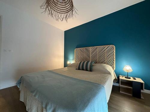 une chambre avec un lit et un mur bleu dans l'établissement Appartement neuf proche Arcachon, à La Teste-de-Buch