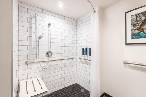 a bathroom with a shower with white tiles at Four Points by Sheraton Spartanburg in Spartanburg