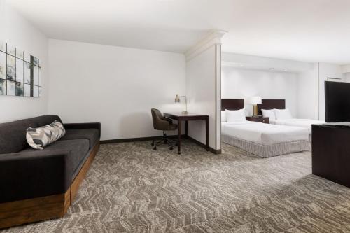 Habitación de hotel con sofá, cama y escritorio. en SpringHill Suites Fresno en Fresno