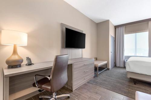 a hotel room with a bed and a desk with a television at Pestana Orlando Suites - Lake Buena Vista in Orlando