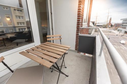 eine Holzbank auf dem Balkon eines Gebäudes in der Unterkunft Koje Sieben I Apartment im Zentrum mit Meerblick in Bremerhaven