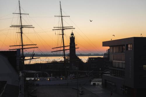 a tall ship in a harbor at sunset at Koje Sieben I Apartment im Zentrum mit Meerblick in Bremerhaven