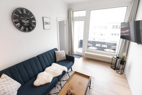 a living room with a blue couch and a clock at Koje Sieben I Apartment im Zentrum mit Meerblick in Bremerhaven
