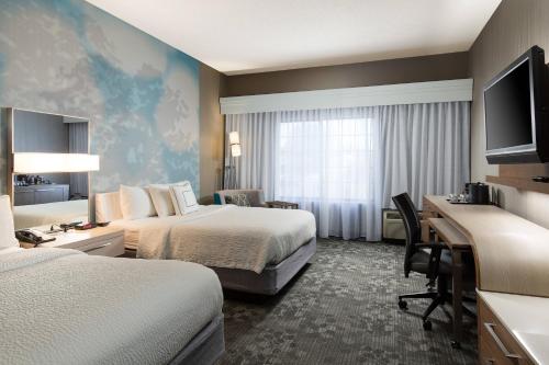 a hotel room with two beds and a desk at Courtyard Kansas City East/Blue Springs in Blue Springs