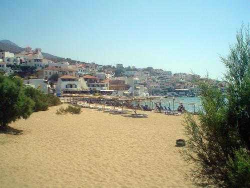 a beach with a bunch of chairs and buildings at Bella Vista in Batsi