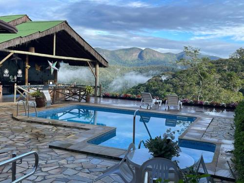 a resort with a pool and mountains in the background at Pousada R.N.C. Nosso Paraíso in Teresópolis
