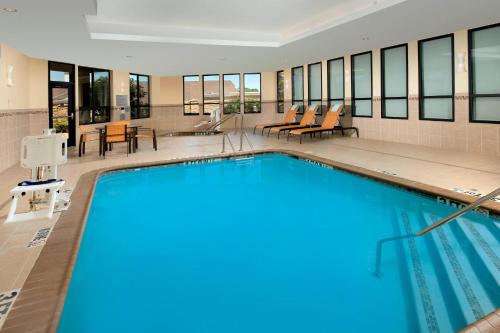 a large swimming pool in a building with tables and chairs at Courtyard by Marriott Tyler in Tyler