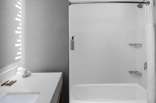 a white bathroom with a shower and a sink at Courtyard by Marriott San Angelo in San Angelo