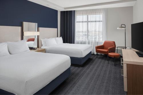 ein Hotelzimmer mit 2 Betten und einem Stuhl in der Unterkunft Courtyard by Marriott San Angelo in San Angelo