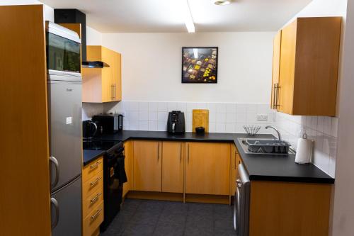 a kitchen with black counter tops and wooden cabinets at Lovely 1-Bed Apartment in Hackney London in London