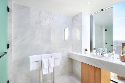 a white bathroom with a sink and a mirror at JW Marriott Parq Vancouver in Vancouver