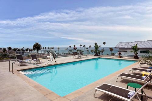 a swimming pool with chairs and the ocean in the background at SpringHill Suites by Marriott San Diego Oceanside/Downtown in Oceanside