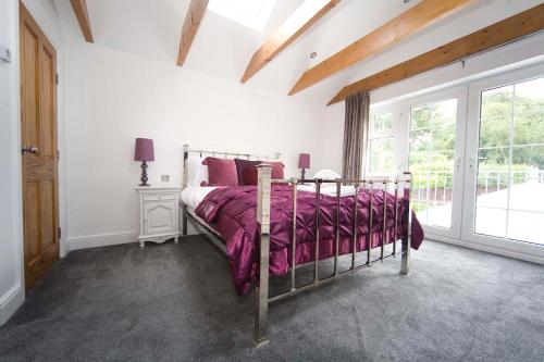 a bedroom with a bed with purple sheets and a window at Wolviston Cottage in Wolviston